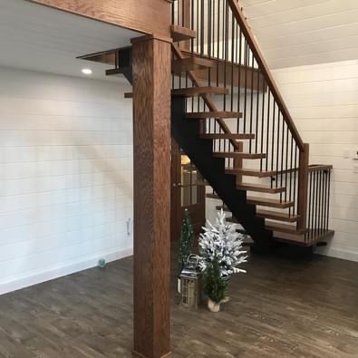 Modern open riser staircase with black steel stringer, hardwood stair treads, and metal railings installed in a custom home